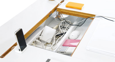 Une grande trappe avec un panneau coulissant permet d'accéder facilement aux prises, chargeurs et alimentations cachés dans le bureau Studio Desk